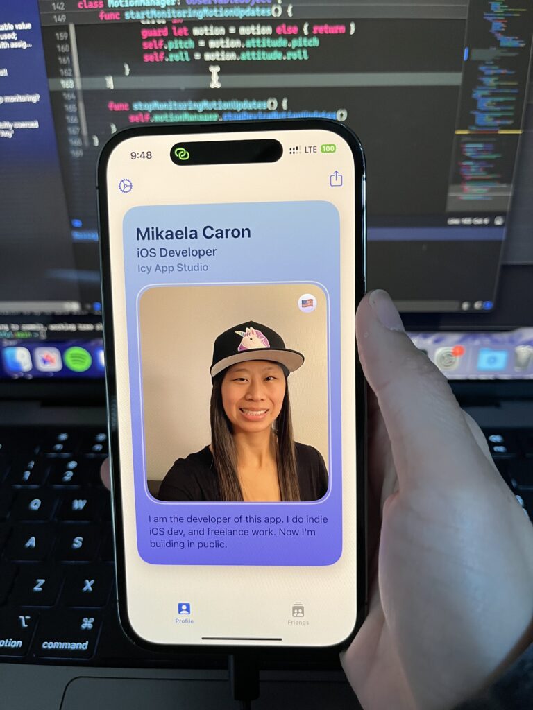 Fruitful Card. A blue to purple gradient card with the information Mikaela Caron, iOSDeveloper, Icy App Studio, a small american flag in the top right of an image of Mikaela and summary: "I am the developer of this app. I do indie iOS dev, and freelance work. Now I'm building in public.